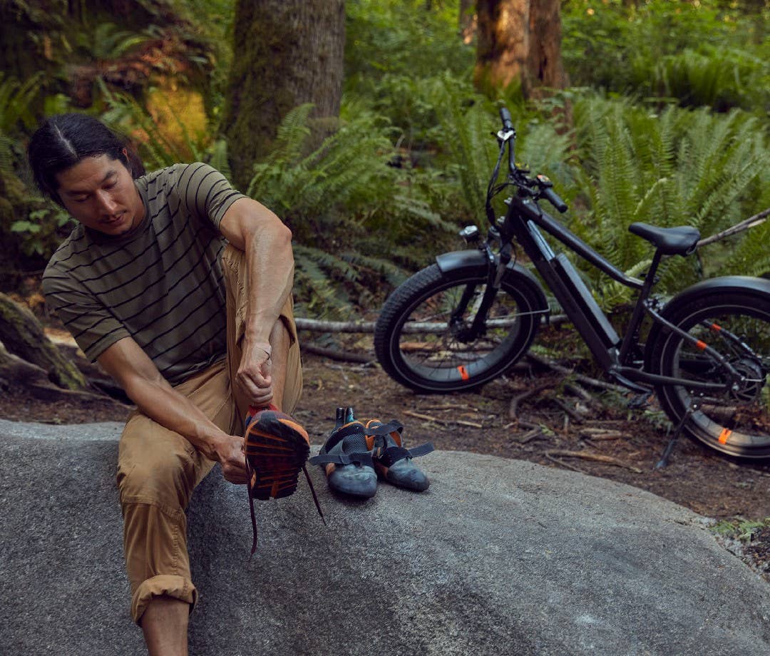 Climber wearing rock climbing shoes with electric bike behind him